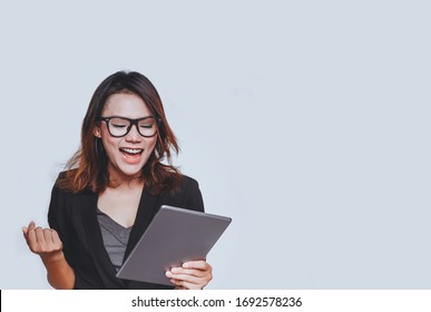 Asian Woman Smiled In A Happy Mood As She Stared At Her IPad. On White Background