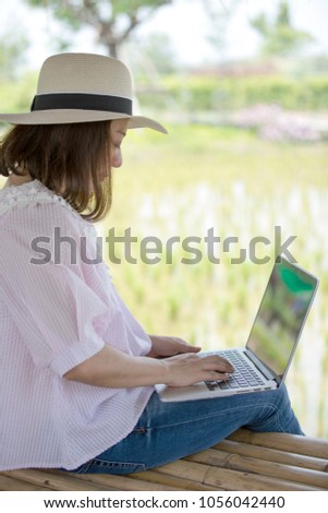 Asian woman in smiling face using laptop, workplace in tree garden. Concept of Asian woman lifestyle.