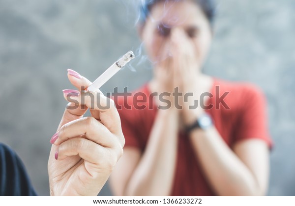 Asian woman smoking cigarette\
near people in family smelling pollution, passive smoking\
concept