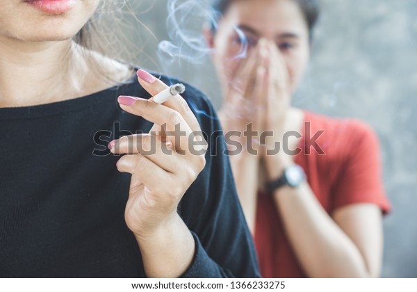 Asian woman smoking
cigarette near people in family smelling pollution,passive smoking
concept