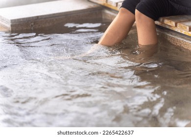 Asian woman soaking feet in hot water and writing journey memories in diary book. Attractive girl resting at wooden seat pavilion covered in snow during travel village in Japan on winter vacation - Powered by Shutterstock