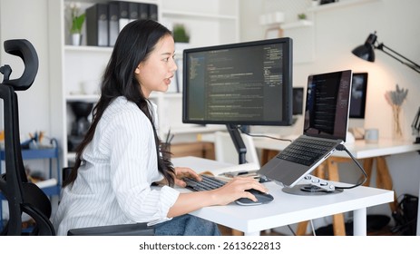 Asian woman software engineer coding on multiple screens.