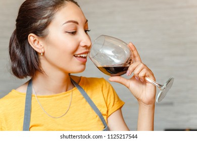 Asian Woman Sommelier In Apron Holding Red Wine Glass