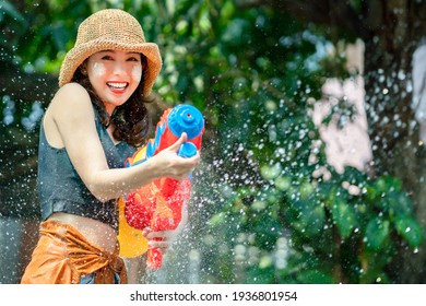 Asian woman splashed by water for Songkran festival. She uses a water gun.