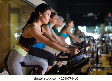 Asian Woman In Sportive Activewear Training On Bike In Spin Class At Gym