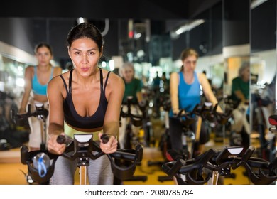 Asian Woman In Sportive Activewear Training On Bike In Spin Class At Gym