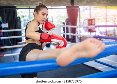 Asian woman in sportswear and boxing gloves kicking at a boxing studio. young woman training boxing in the in the gym.