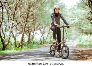 Asian woman in sportswear and helmet while cycling on outdoor background - Powered by Shutterstock