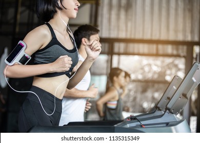 Asian woman in sportswear running on treadmill at gym