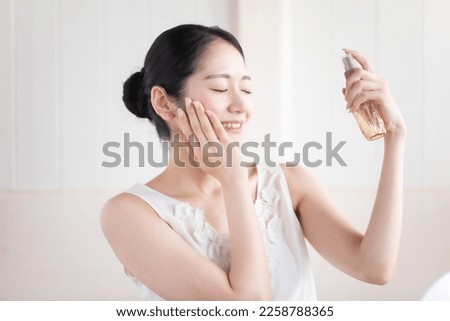 Asian woman spraying mist on her face