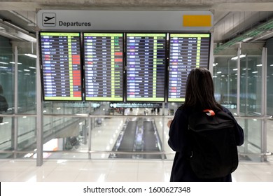 The Asian Woman Standing In Front Of Flight Information Board.