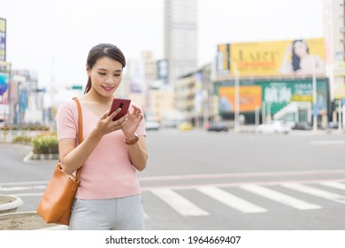 Asian Woman Is Standing On The Street In City And Using Smart Phone While Commuting