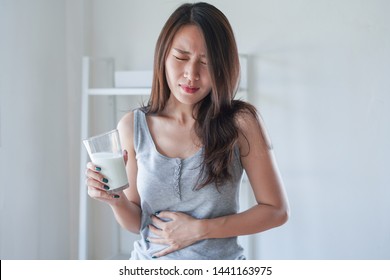 Asian Woman With Stomach Ache And Pain Holding A Glass Of Milk. Dairy Intolerant, Lactose Intolerance, Allergy, Health Care Concept