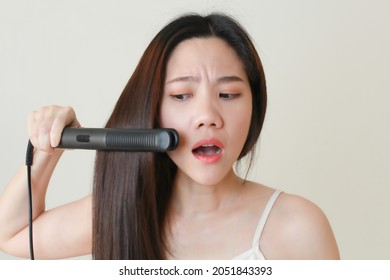 Asian Woman Is Straightening Her  Hair Using Electric Hair Iron Straightener With Shocking Nervous Face