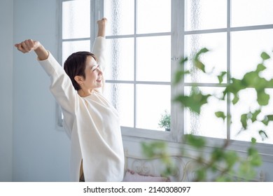 Asian woman stretching with a smile - Powered by Shutterstock