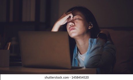 Asian Woman Student Or Businesswoman Work Late At Night. Concentrated And Feel Sleepy At The Desk In Dark Room With Laptop Or Notebook.Concept Of People Workhard And Burnout Syndrome.