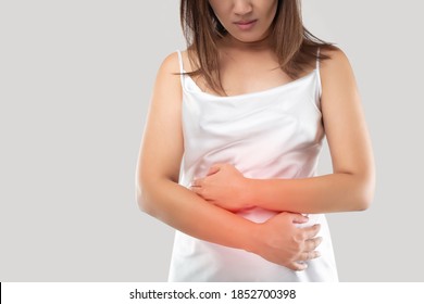 Asian Woman Suffering From Stomachache On Gray Background. Irritable Bowel Syndrome Or IBS. Space Left Side