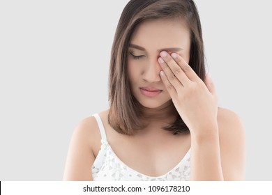 Asian woman suffering from strong eye pain against a gray background. Female has a pain in the eye. Healthcare concept. Having migraine