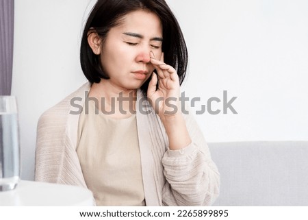 Asian woman suffering from stuffy nose having runny nose and bad breath caused by sinus infection 