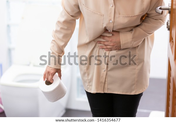 アジアの女性は 便器の近くで 下痢を起こしているが 女の子は 浴室で腹痛を起こし 女性の月経時間の痛み 腹の下痢による手 胃の健康に関する問題を抱えている の写真素材 今すぐ編集