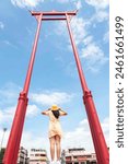 Asian woman in sunhat traveling at Giant Swing at Wat Suthat temple the landmark in Bangkok, Thailand.