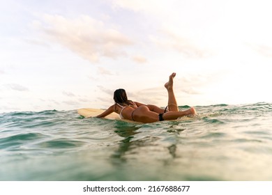 Asian Woman Surfer Paddling Surfboard And Riding The Wave In The Sea At Tropical Beach At Sunset. Healthy Female Enjoy Outdoor Activity Lifestyle And Water Sport Exercise Surfing On Summer Vacation