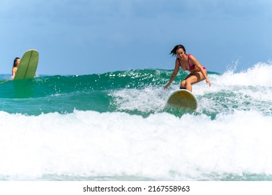 Asian Woman Surfer Surfing And Riding Surfboard  The Wave In The Sea At Tropical Beach In Sunny Day. Healthy Female Enjoy Outdoor Activity Lifestyle And Water Sport Exercise Surfing On Summer Vacation