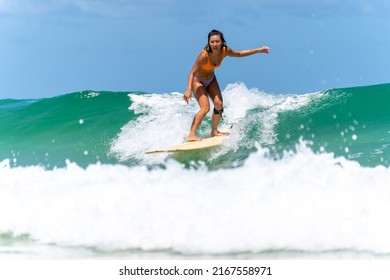 Asian Woman Surfer Surfing And Riding Surfboard  The Wave In The Sea At Tropical Beach In Sunny Day. Healthy Female Enjoy Outdoor Activity Lifestyle And Water Sport Exercise Surfing On Summer Vacation