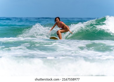 Asian Woman Surfer Surfing And Riding Surfboard  The Wave In The Sea At Tropical Beach In Sunny Day. Healthy Female Enjoy Outdoor Activity Lifestyle And Water Sport Exercise Surfing On Summer Vacation