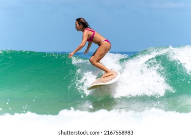 Asian Woman Surfer Surfing And Riding Surfboard  The Wave In The Sea At Tropical Beach In Sunny Day. Healthy Female Enjoy Outdoor Activity Lifestyle And Water Sport Exercise Surfing On Summer Vacation