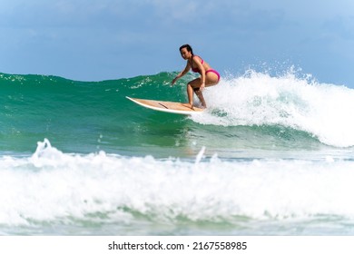 Asian Woman Surfer Surfing And Riding Surfboard  The Wave In The Sea At Tropical Beach In Sunny Day. Healthy Female Enjoy Outdoor Activity Lifestyle And Water Sport Exercise Surfing On Summer Vacation