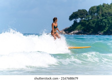 Asian Woman Surfer Surfing And Riding Surfboard  The Wave In The Sea At Tropical Beach In Sunny Day. Healthy Female Enjoy Outdoor Activity Lifestyle And Water Sport Exercise Surfing On Summer Vacation