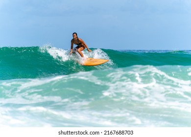 Asian Woman Surfer Surfing And Riding Surfboard  The Wave In The Sea At Tropical Beach In Sunny Day. Healthy Female Enjoy Outdoor Activity Lifestyle And Water Sport Exercise Surfing On Summer Vacation