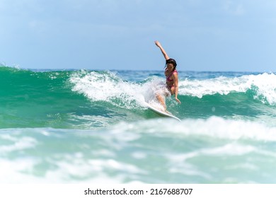 Asian Woman Surfer Surfing And Riding Surfboard  The Wave In The Sea At Tropical Beach In Sunny Day. Healthy Female Enjoy Outdoor Activity Lifestyle And Water Sport Exercise Surfing On Summer Vacation