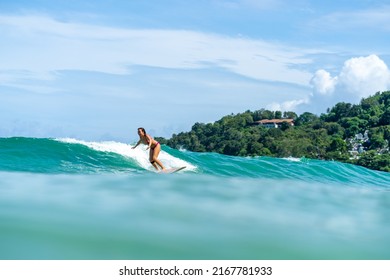 Asian Woman Surfer Surfing And Riding Surfboard  The Wave In The Sea At Tropical Beach In Sunny Day. Healthy Female Enjoy Outdoor Activity Lifestyle And Water Sport Exercise Surfing On Summer Vacation