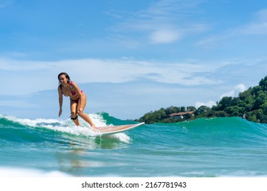 Asian Woman Surfer Surfing And Riding Surfboard  The Wave In The Sea At Tropical Beach In Sunny Day. Healthy Female Enjoy Outdoor Activity Lifestyle And Water Sport Exercise Surfing On Summer Vacation