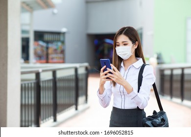 Asian Woman With Surgical Mask Face Protection - She Use A Smartphone While Walking Outside In The City