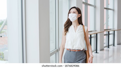 Asian woman with surgical mask face protection - she commutes between home and workplace in the city - Powered by Shutterstock