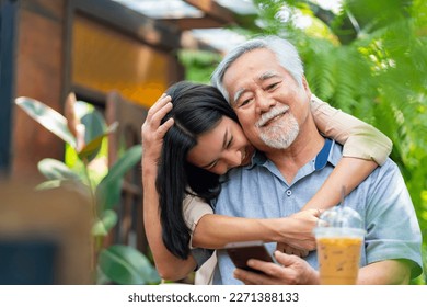 Asian woman surprise hugging elderly father from back at outdoor garden cafe restaurant on summer vacation. Family relationship, holiday celebrating, father's day and old people health care concept - Powered by Shutterstock