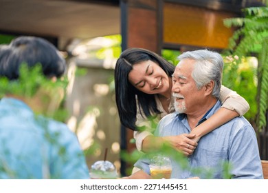 Asian woman surprise hugging elderly father from back at outdoor garden cafe restaurant on summer vacation. Family relationship, holiday celebrating, father's day and old people health care concept - Powered by Shutterstock