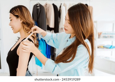 Asian woman tailor measures customers' bodies to make new clothes. Attractive fashion designer dressmaker designing new fashion collections for customers in atelier tailor workshop. Small business - Powered by Shutterstock