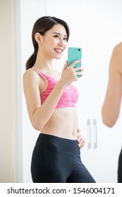 Asian Woman Take Selfie In Front Of Mirror With Sport Wear Happily