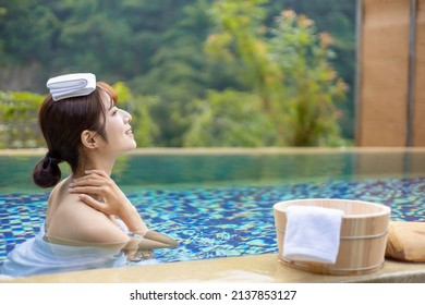 Asian woman taking a bath at hotspring relaxing with towel on head