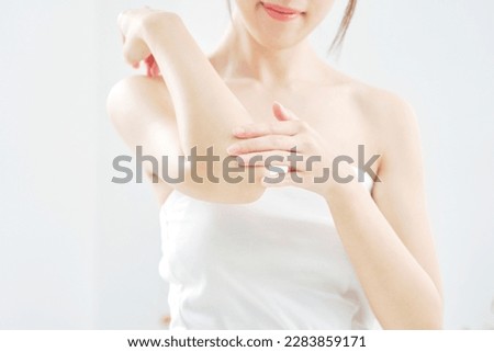 Asian woman taking care of her elbow at home, no face