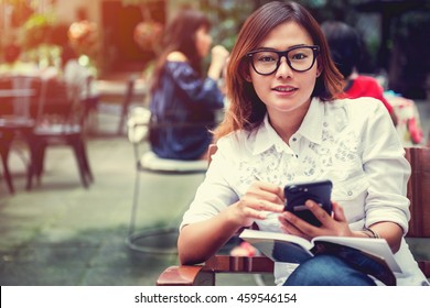 Asian Woman Taking Notes On The Phone With The Intention,Focus Face