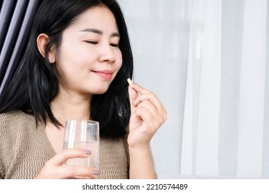 Asian Woman Taking Vitamin C With A Glass  Of Water 