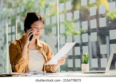 Asian Woman Talking On The Phone, She Is A Salesperson In A Startup Company, She Is Calling Customers To Sell Products And Promotions. Concept Of Selling Products Through Telephone Channels.