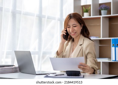 Asian Woman Talking On The Phone, She Is A Salesperson In A Startup Company, She Is Calling Customers To Sell Products And Promotions. Concept Of Selling Products Through Telephone Channels.