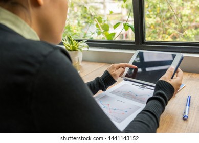 Asian Woman Tapping Tablet Screen With Graph Document On Table