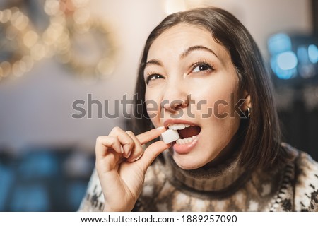 Asian woman tastes and nibbles a piece of white refined sugar. The concept of excessive consumption of fast carbohydrates and dental health
